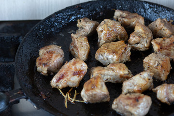 Fried pieces of meat on pan on the stove