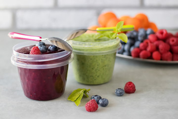 Fruit and berry smoothies and green smoothie. Fresh apricots, raspberries and blueberries on an oval metal plate. Gray background.