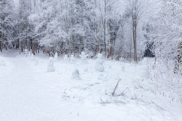 Winter scene in a rest zone near a forest. Benches and snowmen, forest road