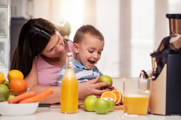 Obraz na płótnie Canvas Mother and child making fresh orange juice