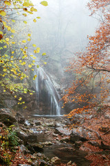 Beautiful waterfall in autumn forest in crimean mountains. Stones with moss in the water.