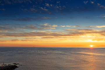 Sunset on the black sea. The Resort Of Gelendzhik. Beautiful clouds, blue sky, sun on the horizon. Beautiful stones in the foreground