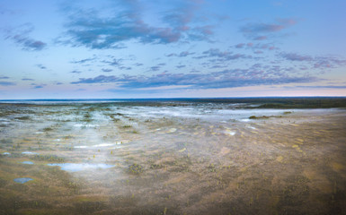 Warmly colored sunrise over a foggy swamp. Aerial view of stunning landscape at peat bog at Kemeri national park in Latvia. Wooden trail leading along the lake surrounded by pounds and forest. 