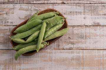 whole fresh peas on wooden table