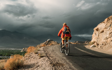 Obraz premium Bike tourist rides on Himalaya mountain road on way to buddist monastery