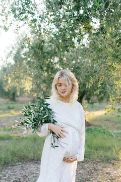 Pregnant woman keeping eyes closed in olive grove