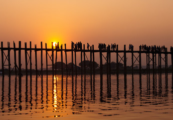 Silhouetted people on U Bein Bridge at sunset, Amarapura, Mandalay region, Myanmar. Burma. The longest and oldest teak wooden bridge in the world