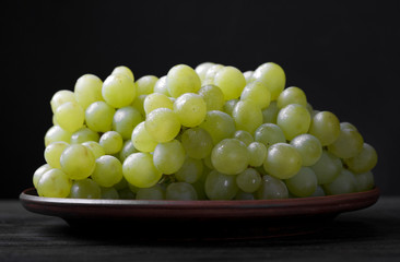 .green grapes in a plate on a black background