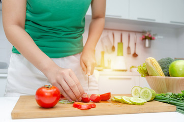 Diet. young pretty woman in green shirt cutting cooking and knife preparing fresh vegetables salad for good healthy in kitchen at home, healthy lifestyle, cooking, healthy food and dieting concept