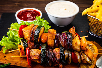 Kebabs - grilled meat with french fries and vegetables wooden background