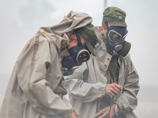 Soldiers in smoke wear chemical protection suits