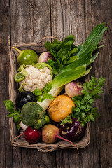 Basket with vegetables on a wooden background. Cauliflower, broccoli, radish, parsnip, leek, kohlrabi