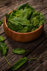 Spinach in a wooden plate on a wooden background