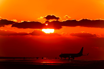 Plakat 美しい夕焼け雲の空・夕日を背景に滑走路を走行する航空機(シルエット)景色 　撮影場所：日本(秋) 「九州・熊本県」Beautiful sunset Cloud sky ・ Aircraft (silhouette) scenery running on the runway against the backdrop of the setting sun Location: Japan 