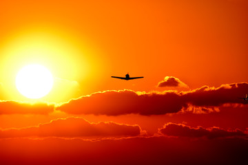 Fototapeta na wymiar 美しい夕焼け雲の空・夕日を背景に飛行する航空機・セスナ機(シルエット)景色 　撮影場所：日本(秋) 「九州・熊本県」Beautiful sunset Cloud sky, aircraft flying against the backdrop of the setting sun, Cessna aircraft (silhouette) scenery Location: Japan
