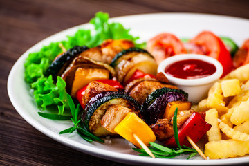 Kebabs - grilled meat with french fries and vegetables wooden background