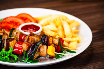 Kebabs - grilled meat with french fries and vegetables wooden background