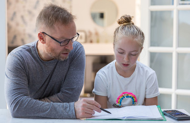 Father helping his 11 year old daughter with a maths assignment,