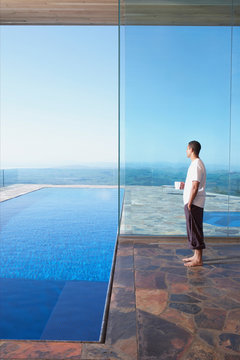 African American man standing looking at view with cup of coffee