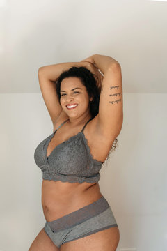 A beautiful plus size woman in her twenties lounging at home in a bra and underwear