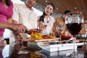 Group of multi-ethnic friends prepping for dinner party in the kitchen