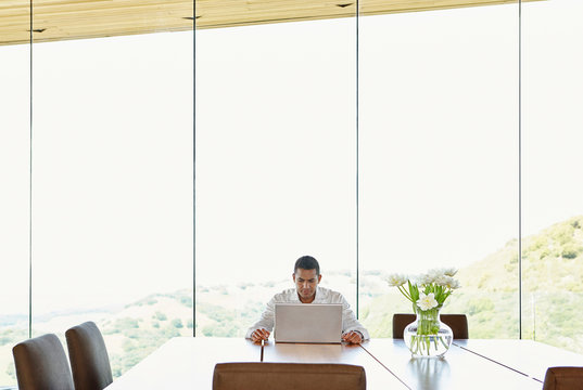 Mature African American man working on computer at dining room table at home