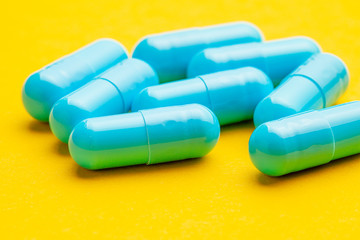Blue tablets in capsules. Yellow background.