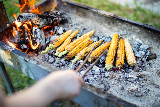 Woman bakes corn on the BBQ