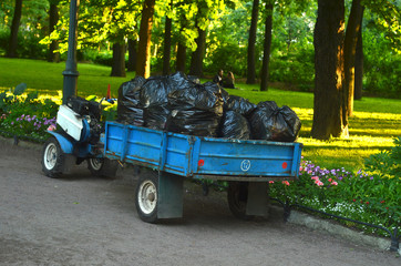Tractor and Trailer with many bags of plant garbage in the garden.Periodic garbage collection.