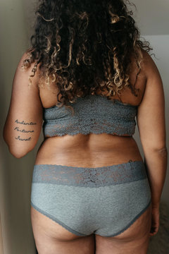 A beautiful plus size woman in her twenties lounging at home in a bra and underwear