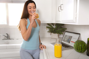 Sporty fit woman drinking fresh glass of orange juice in the morning, healthy lifestyle, fitness, exercise, wellness