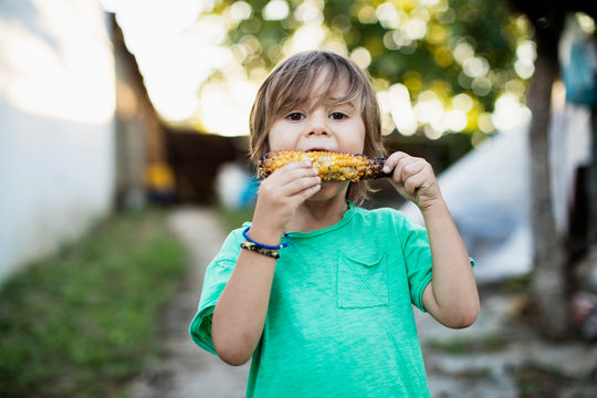 3 year old boy eating baked corn