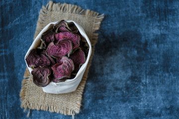 vegetarian pile of healthy beet chips Purple Baked Beet Chips Vegan snacks, vegetable chips in canvas bag and ceramic bowl, rustic still life, selective focus.