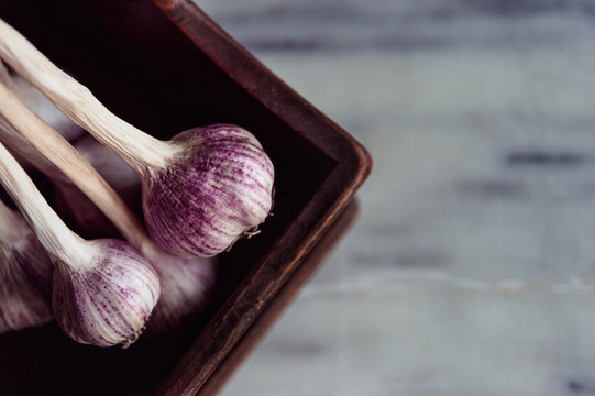 Close up of garlic bulbs on a wooden tray on a marble bench