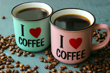 I love coffee. glass Cup close-up with the name I love coffee. Grey grunge background and lots of scattered coffee beans. Copy space