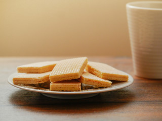Waffles on a white plate and a cup of hot tea on a wooden table. Breakfast concept.