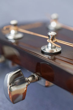 Cose-up of acoustic guitar tuning peg and strings