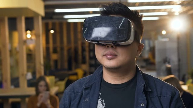 Japanese business man wearing virtual reality VR glasses on the modern office background.