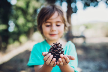 3 year old boy holding a pine cone