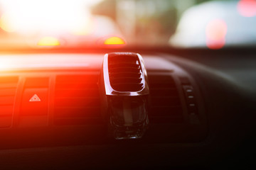 A small glass bottle with perfume for a car is fixed on the diffusers, an air diffuser in the car.