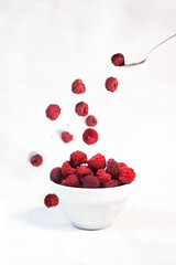 fresh red raspberries falling isolated on white background