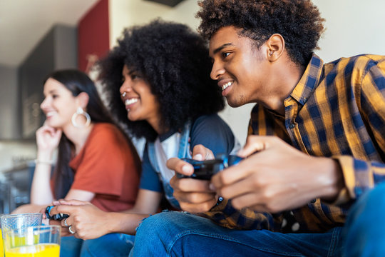 Group of happy young friends playing video games at home