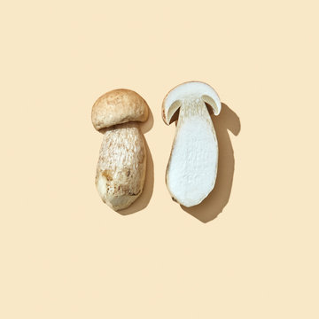 Halves of fresh organic mushroom on a beige background with reflection of shadows and copy space. Flat lay