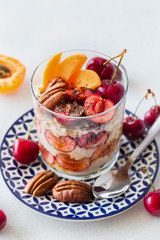 Healthy breakfast: overnight oats with fresh black cherries, peaches and pecans in a glass 