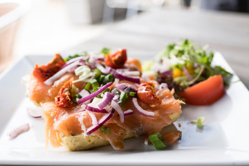 baguette with salmon, red onion, salad, dried tomatoes and leeks