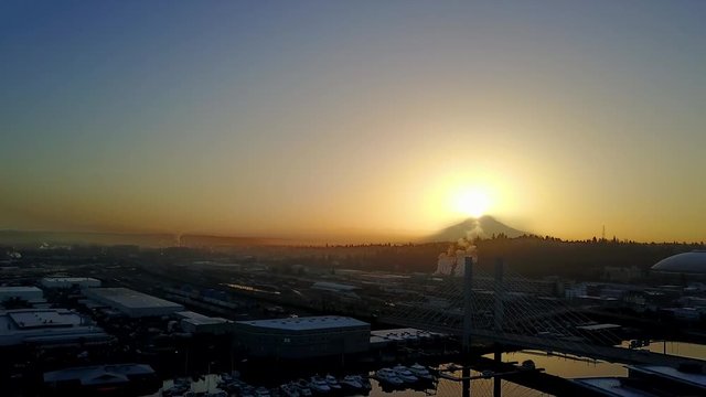 Aerial shot revealing the city of Tacoma, Washington with the sunrise peaking over Mount Rainier.