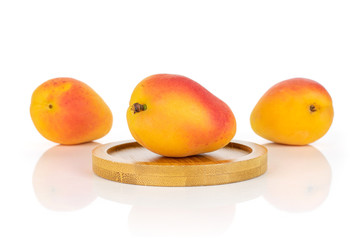 Fototapeta na wymiar Group of three whole fresh orange apricot on a round bamboo coaster isolated on white background