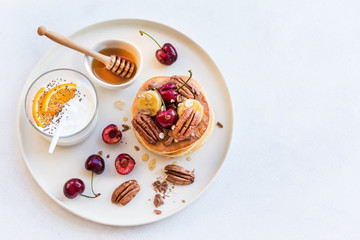 Breakfast concept. Pancakes with black cherries, bananas, pecans, yogurt and honey.