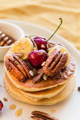 Breakfast concept. Pancakes with black cherries, bananas, pecans, yogurt and honey.
