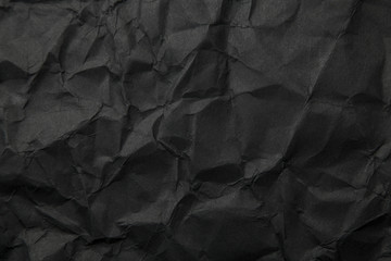 Texture of black crumpled paper. Dark paper background with chaotic bends. A sheet of black...